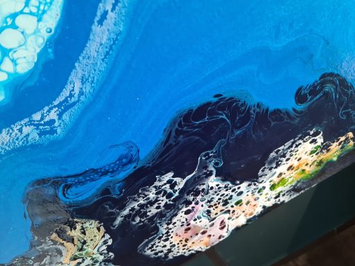 Blaue und schwarze Farbschichten mit bunten Akzenten in fluidem Muster.
