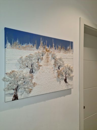 Gemälde mit einer schneebedeckten Landschaft und Bäumen unter blauem Himmel.
